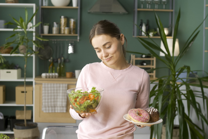 mujer con bol de ensalada y plato con dulces