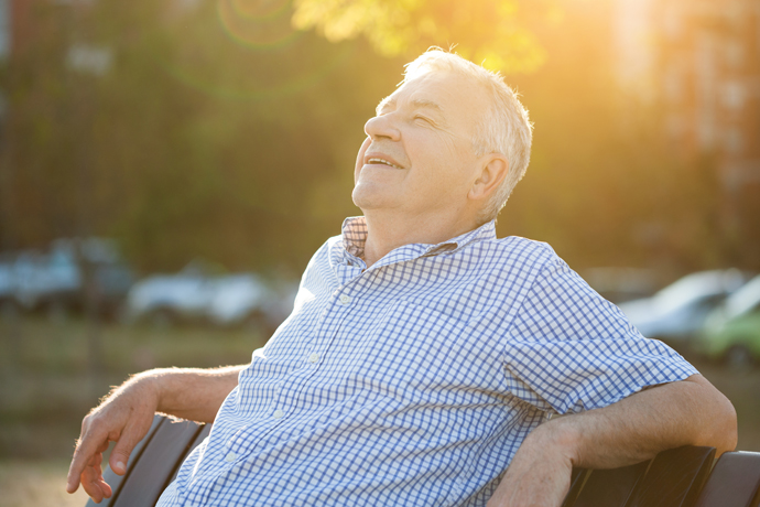 Hombre disfrutando del sol en una banca en el parque