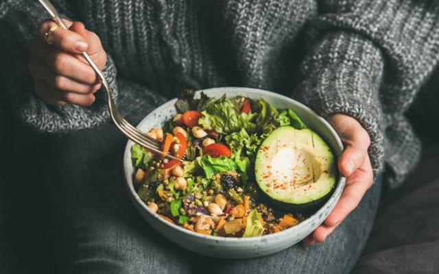 Mujer sujetando plato de ensalada con aguacate y verdura