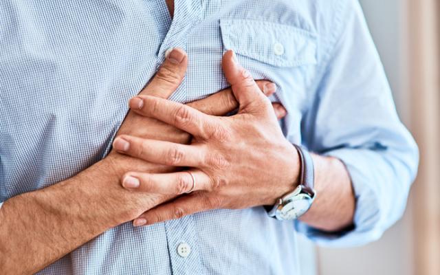 hombre sujetándose con las manos por la presión en el pecho y la falta de aire