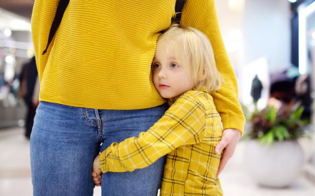 Niña pequeña agarrada a la pierna de su madre