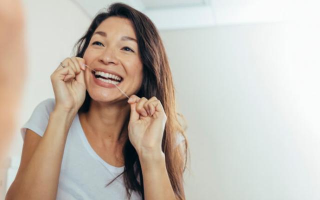 Mujer utilizando el hilo dental después del cepillado.