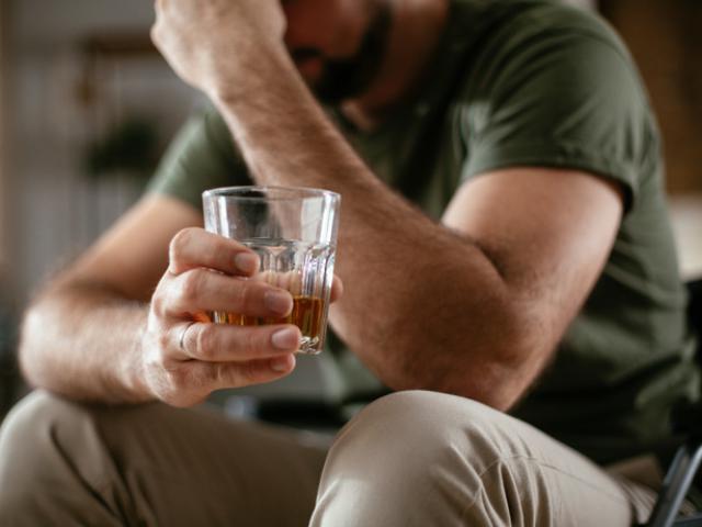 Hombre sujetando un vaso con licor