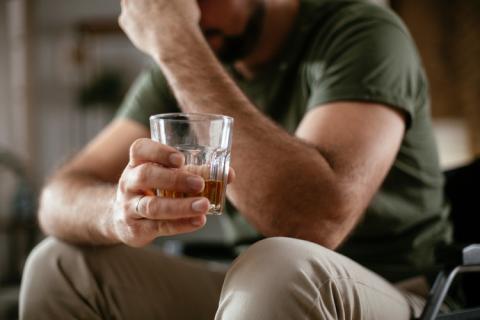 Hombre sujetando un vaso con licor
