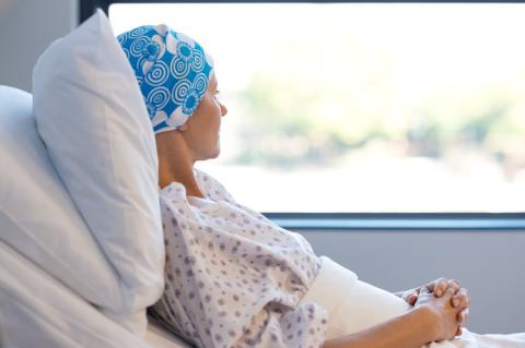 Mujer con cáncer tumbada en cama de hospital