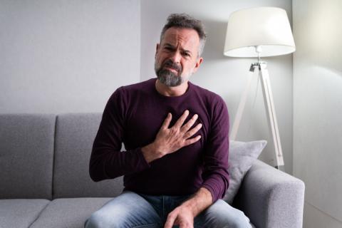 Hombre quejándose de dolor por no saber cómo bajar el colesterol de forma natural.