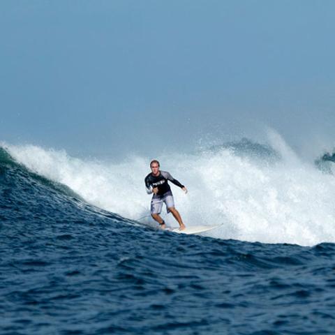 David montando una ola en su tabla de surf.